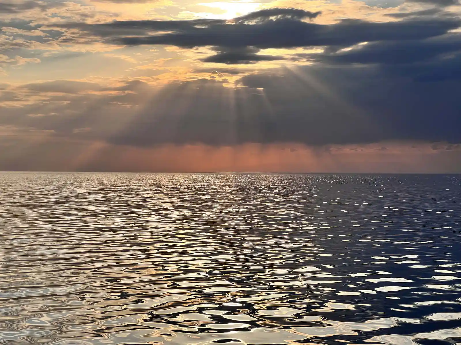 Sun rays breaking through clouds over the rippled waters of Issyk-Kul Lake at sunset